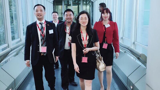 Three men and two women walking along a Parliament House corridor.