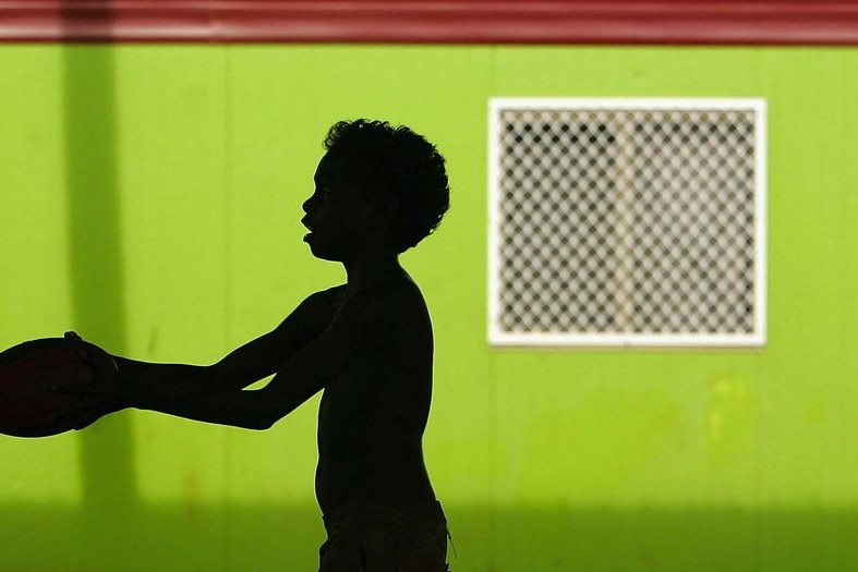 An Aboriginal child plays with a football