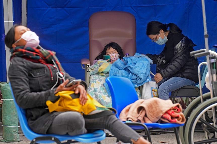 Paitents waiting outside Hong Kong hospital, sitting down and wearing masks