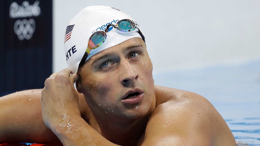 Ryan Lochte leans on the lane rope with his goggles up on his forehead.