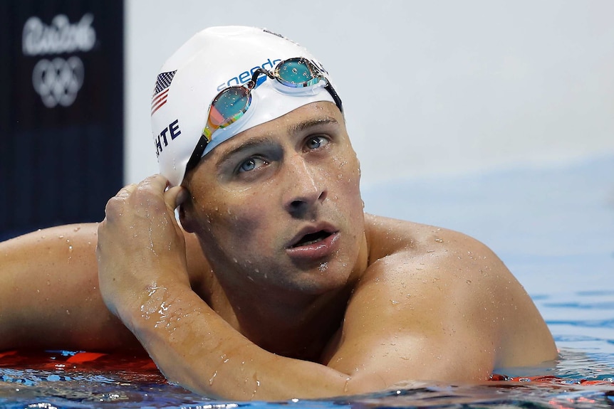 Ryan Lochte leans on the lane rope with his goggles up on his forehead.