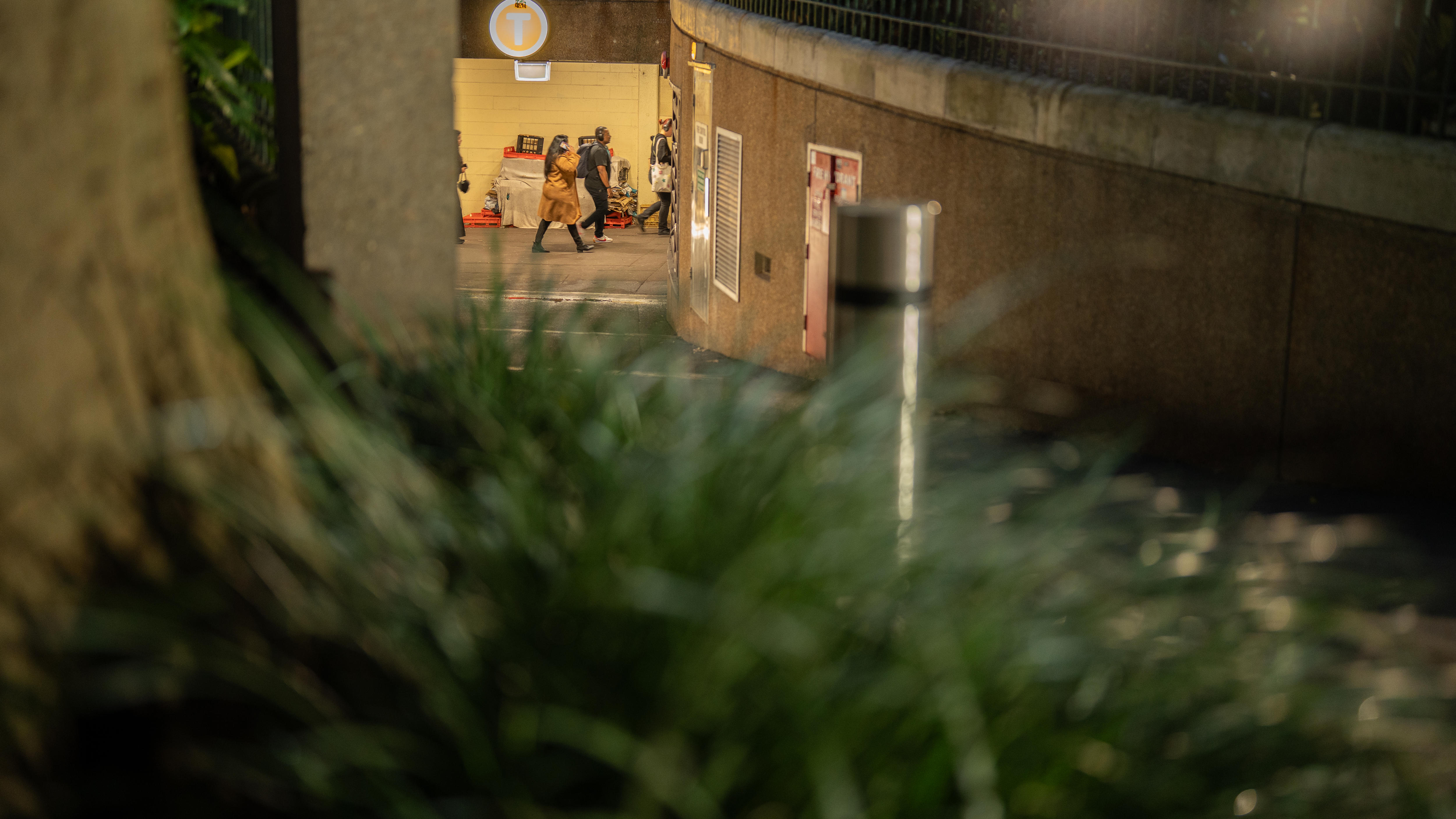 A woman on her phone walks past a homeless person's belongings at St James train station, Sydney.