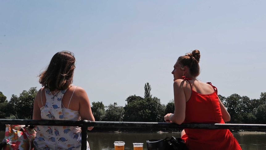 Women sit apart while looking out over a river
