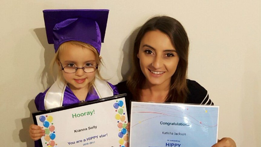 Mother and daughter smile holding HIPPY graduation certificates.