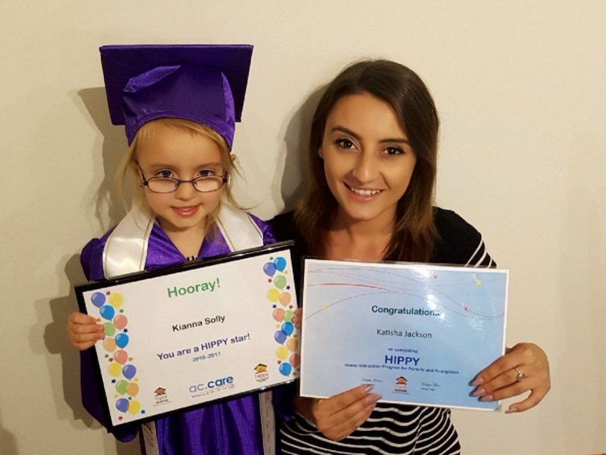 Mother and daughter smile holding HIPPY graduation certificates.