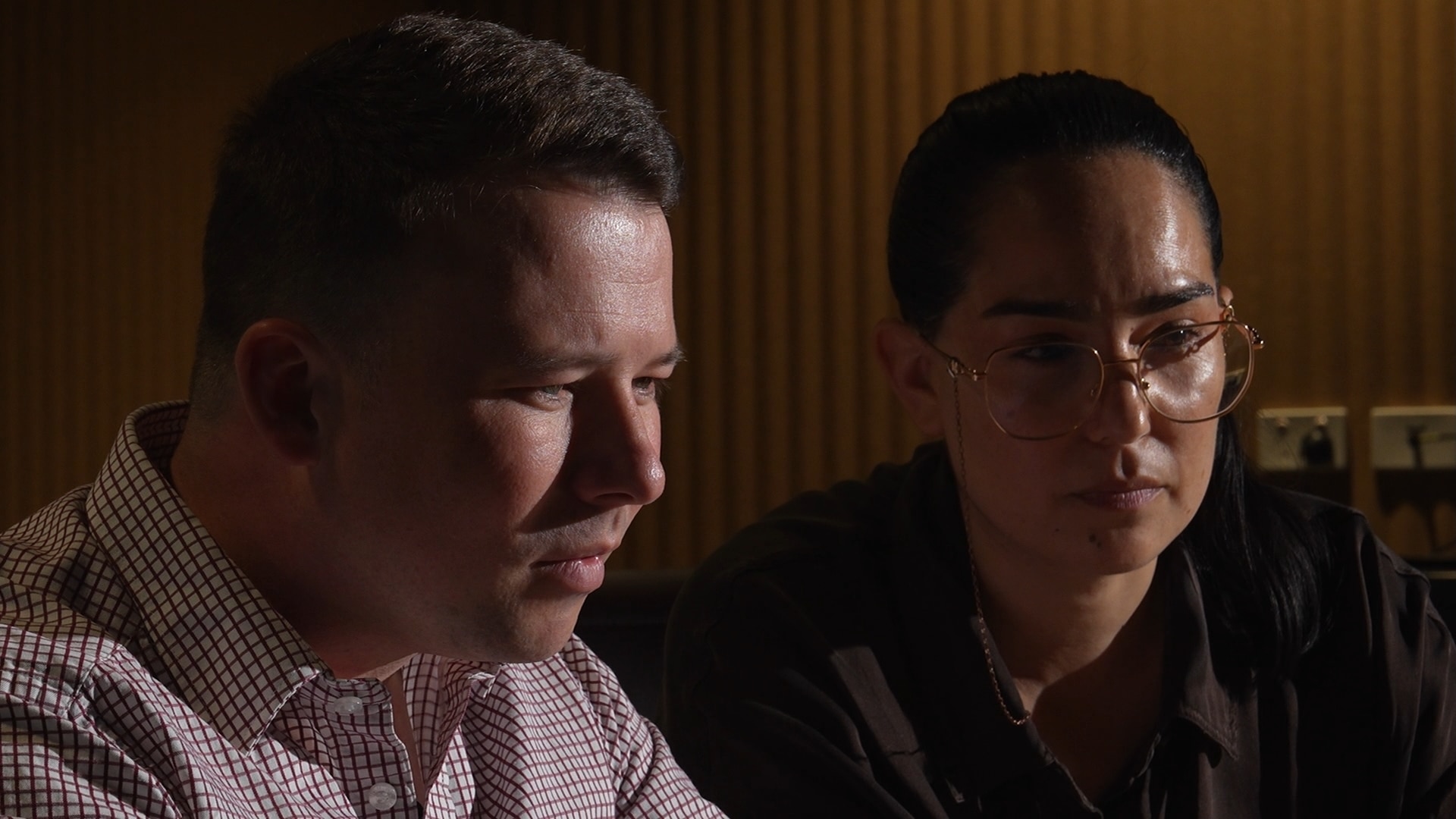 A man and a woman look over a laptop as the screen lights up their face