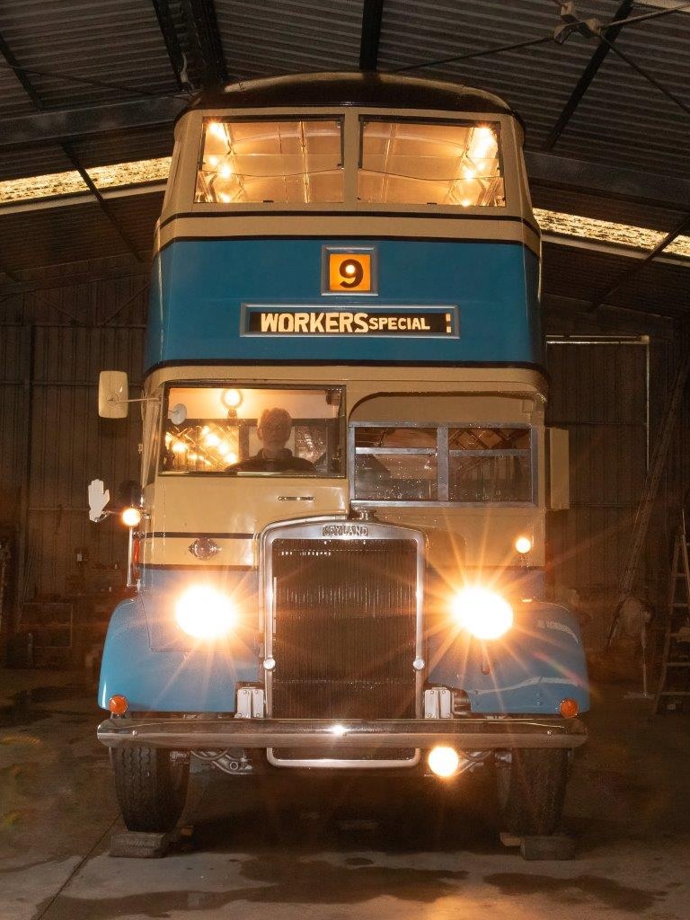Brian sits inside the restored bus with its lights on and blue and cream colour.