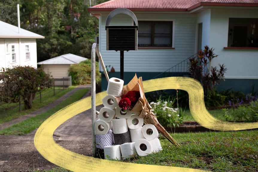 Pile of toilet paper and bunch of flowers sitting by a mailbox in story about being a good neighbour during coronavirus.