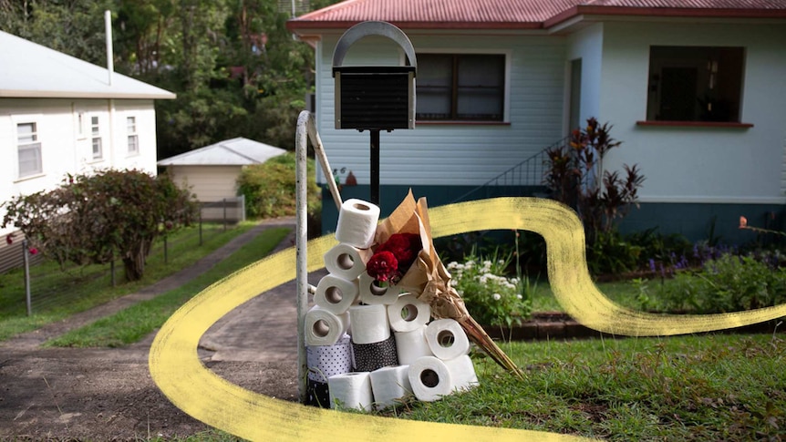 Pile of toilet paper and bunch of flowers sitting by a mailbox in story about being a good neighbour during coronavirus.