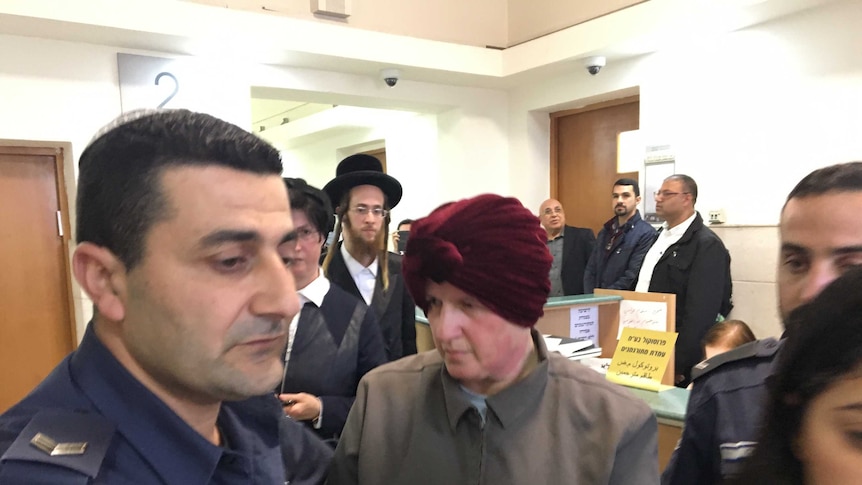 Malka Leifer sits in handcuffs guarded by police