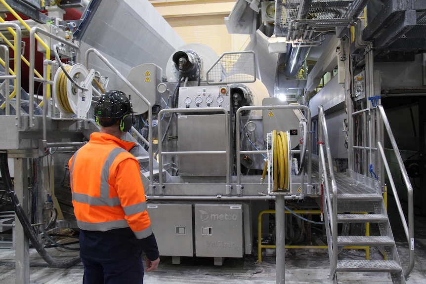 A worker stands in front of machinery in the Boyer paper mill