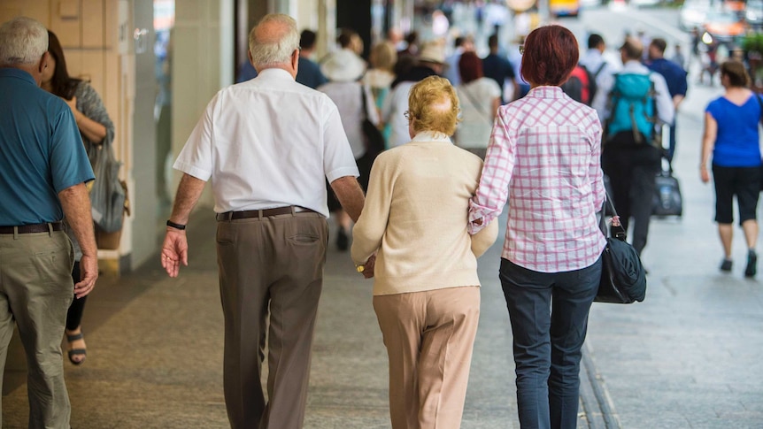 An elderly couple down a mall with the help of a younger woman.