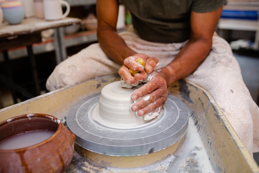 close up of hands molding clay on a pottery wheel 