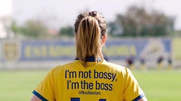 Back of woman's football jersey reads "I'm not bossy, I'm the boss".