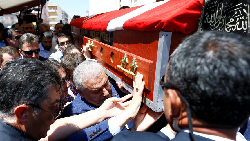 Prime Minister Binali Yildirim carries a coffin.