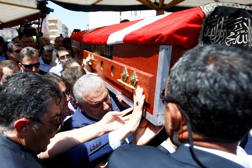 Prime Minister Binali Yildirim carries a coffin.