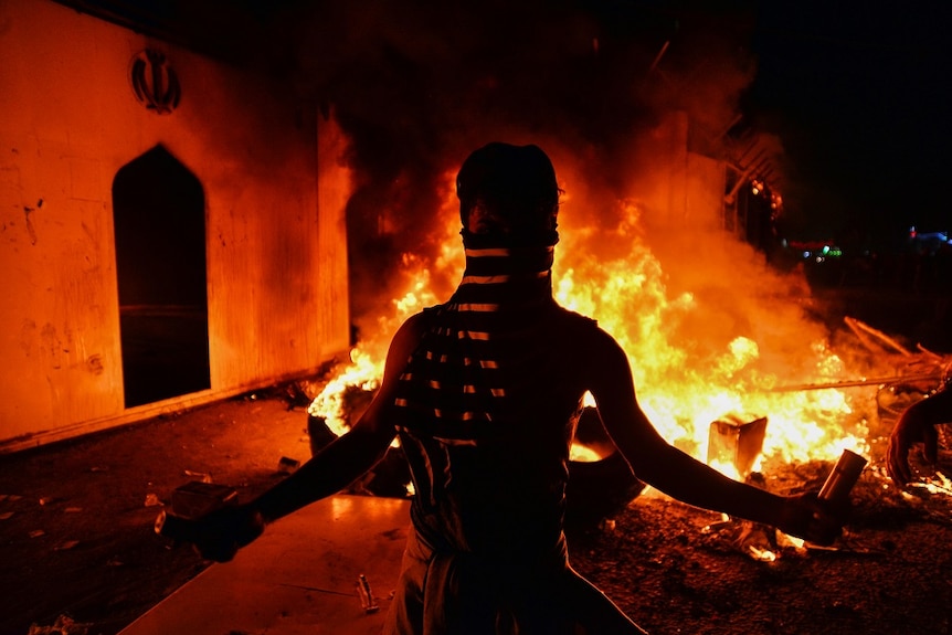 A demonstrator with fire in the background.