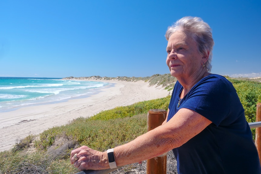 A senior woman with grey hair looking out to sea.
