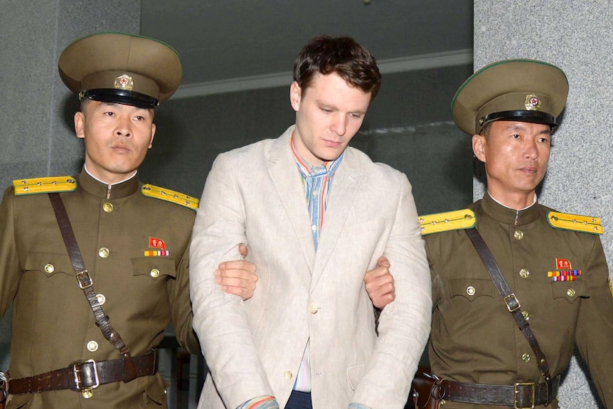 A photo of US student Otto Warmbier being escorted by North Korean guards.