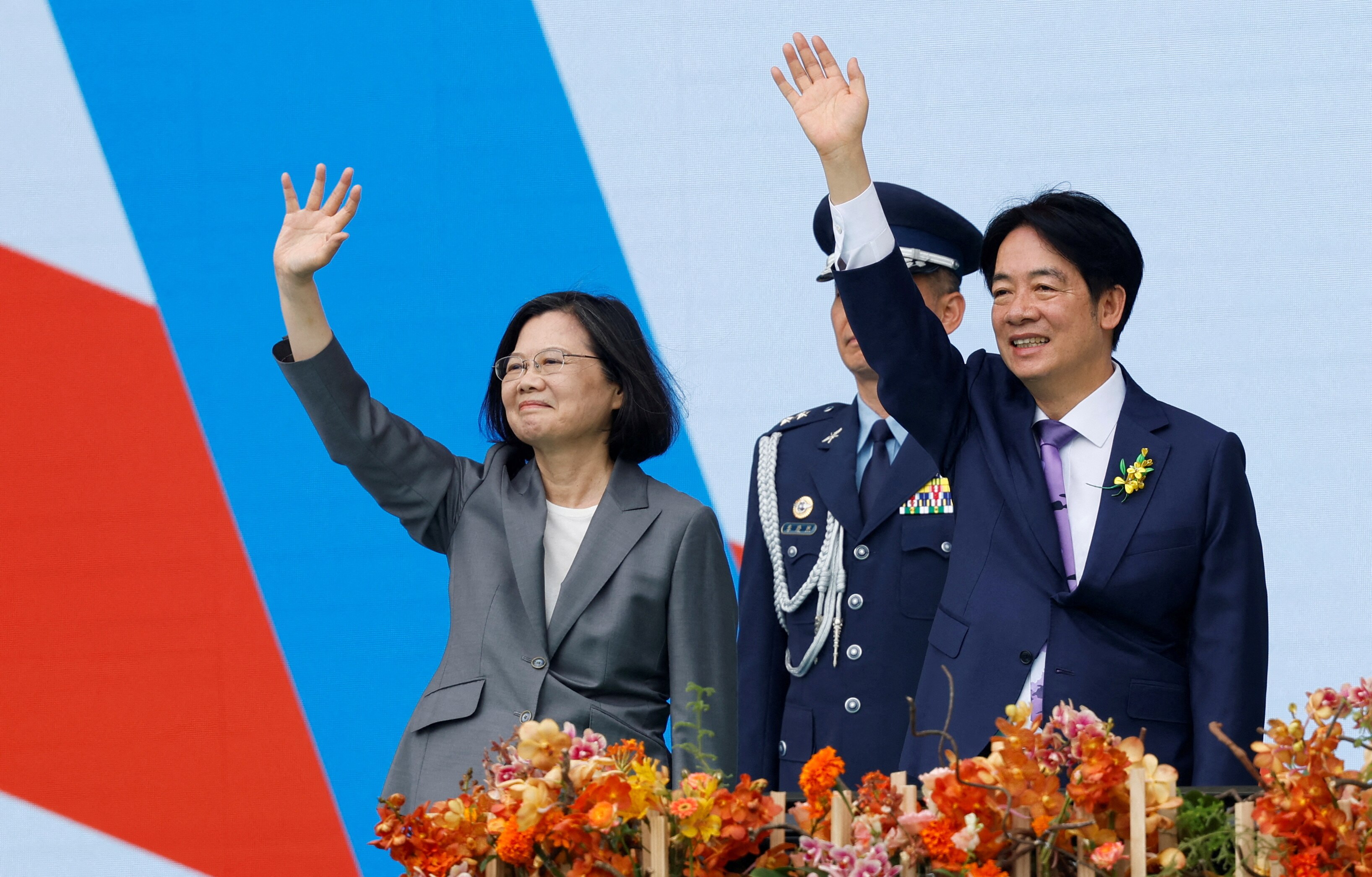 Two politicians from Taiwan waving hands with a police standing in the background. 