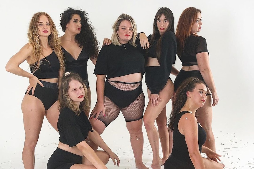 Seven woman in black exercise gear pose for camera