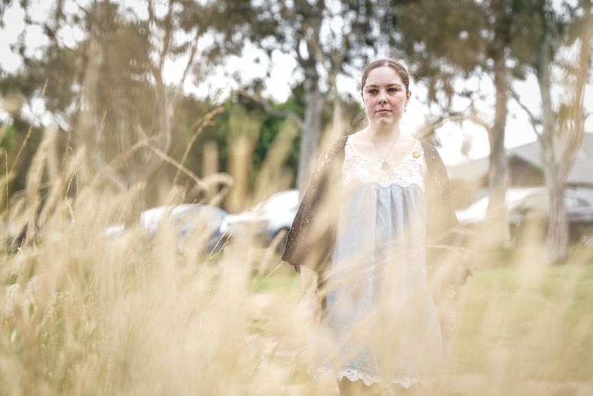 A  young woman seen through tall grass.