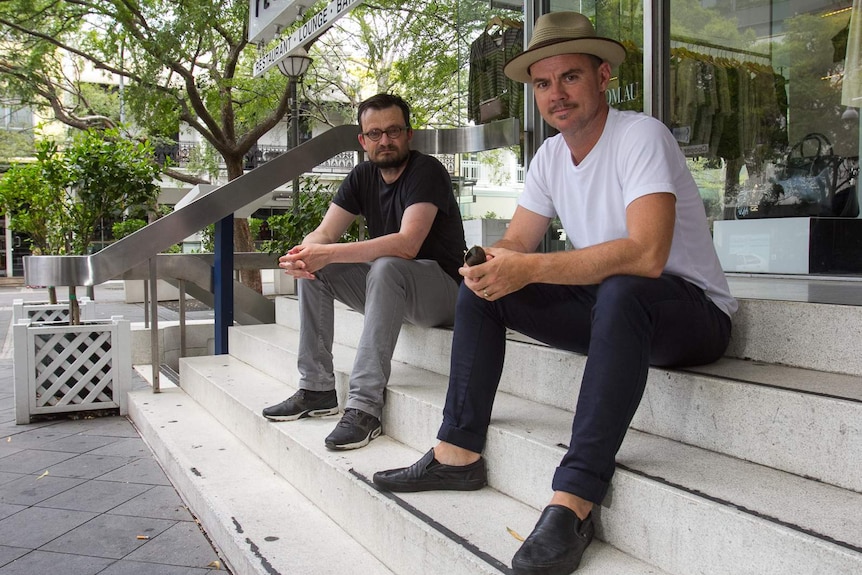 Two men sitting on the terrazzo exterior steps of Gaden House.