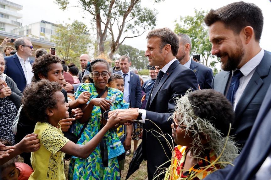 Macron holds hands with a young girl 