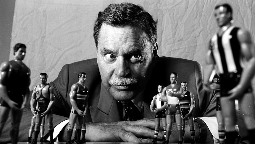 AFL legend Ron Barassi looks over a chessboard with figures of AFL players as the pieces.