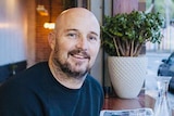 Dean Lloyd sitting in cafe with toast in front of him.