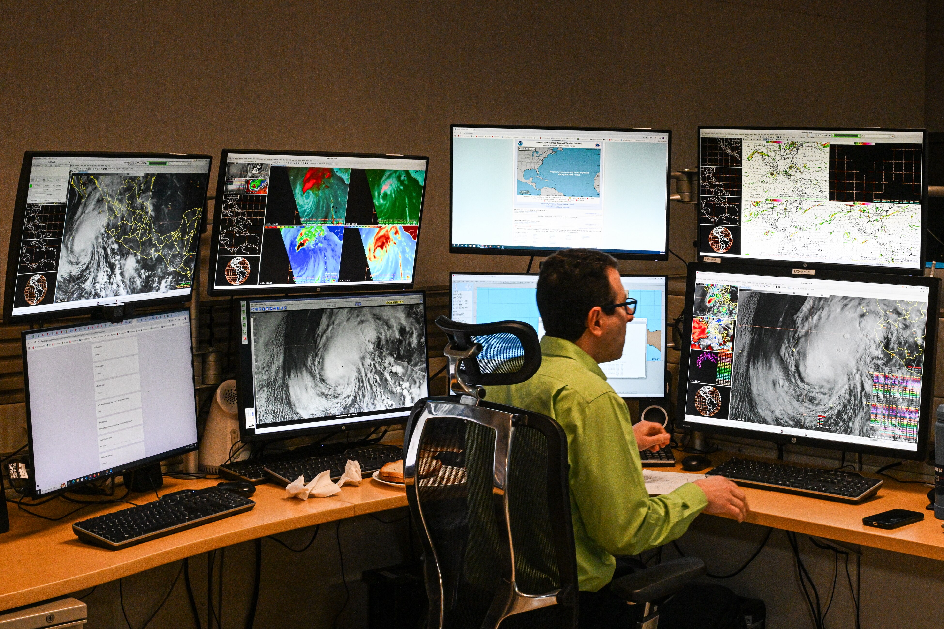 A NOAA scientists at a desk with many screens