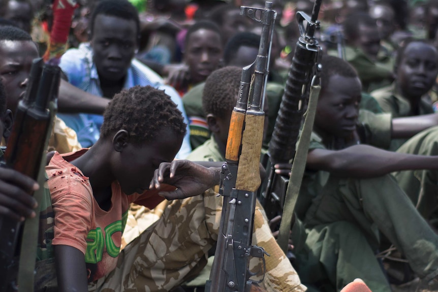 Child soldier sits with rifle