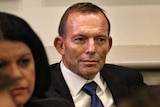 Upper body photo of Tony Abbott sitting in a meeting.