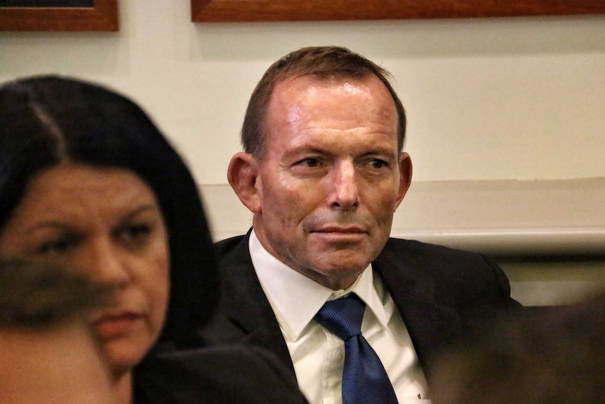 Upper body photo of Tony Abbott sitting in a meeting.