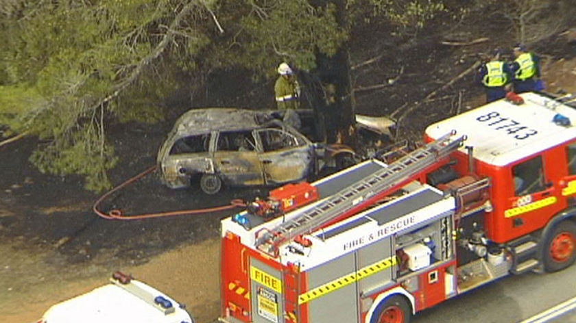 Emergency workers inspect the wreckage of a vehicle that crashed at Jarrahdale