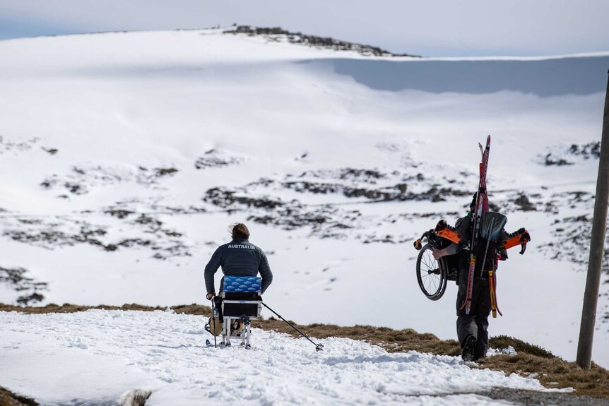 Sam uses a sit-ski to cross-crountry ski to the summit