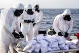 Personnel from HMAS Darwin wear full bodysuits, gloves and masks while preparing to destroy heroin.