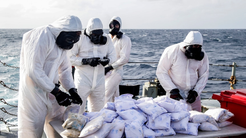 Personnel from HMAS Darwin wear full bodysuits, gloves and masks while preparing to destroy heroin.