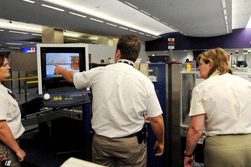 Quarantine Inspection Service officers use an x-ray machine to search passenger bags