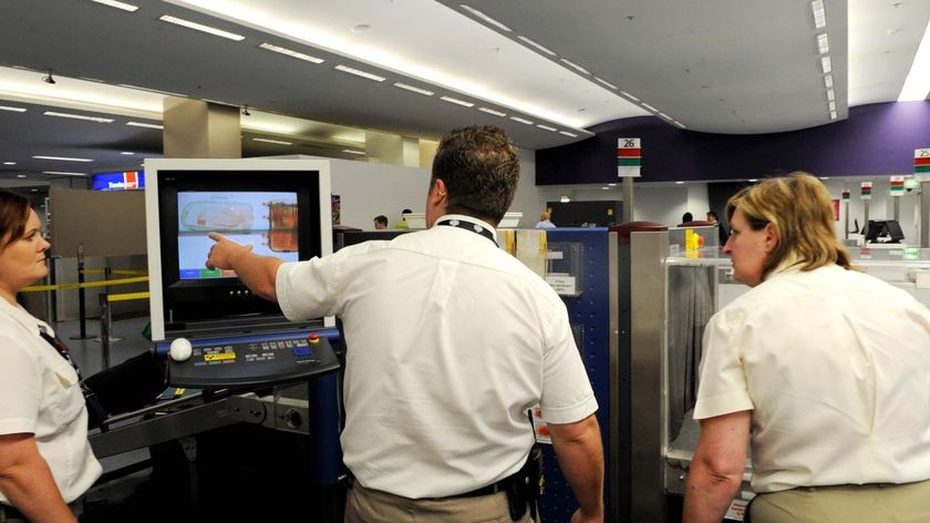 Quarantine Inspection Service officers use an x-ray machine to search passenger bags