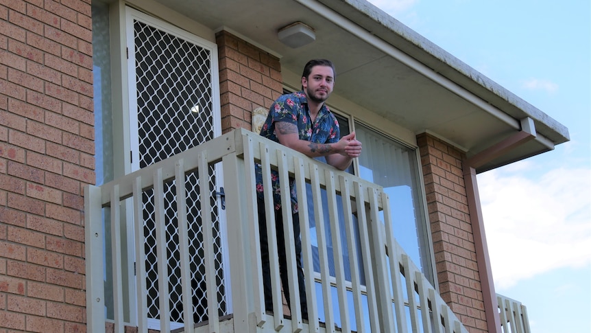 a man leaning on a verandah of a house