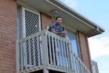 a man leaning on a verandah of a house