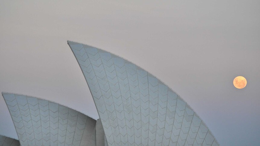 The full moon rises over the Sydney Opera House.