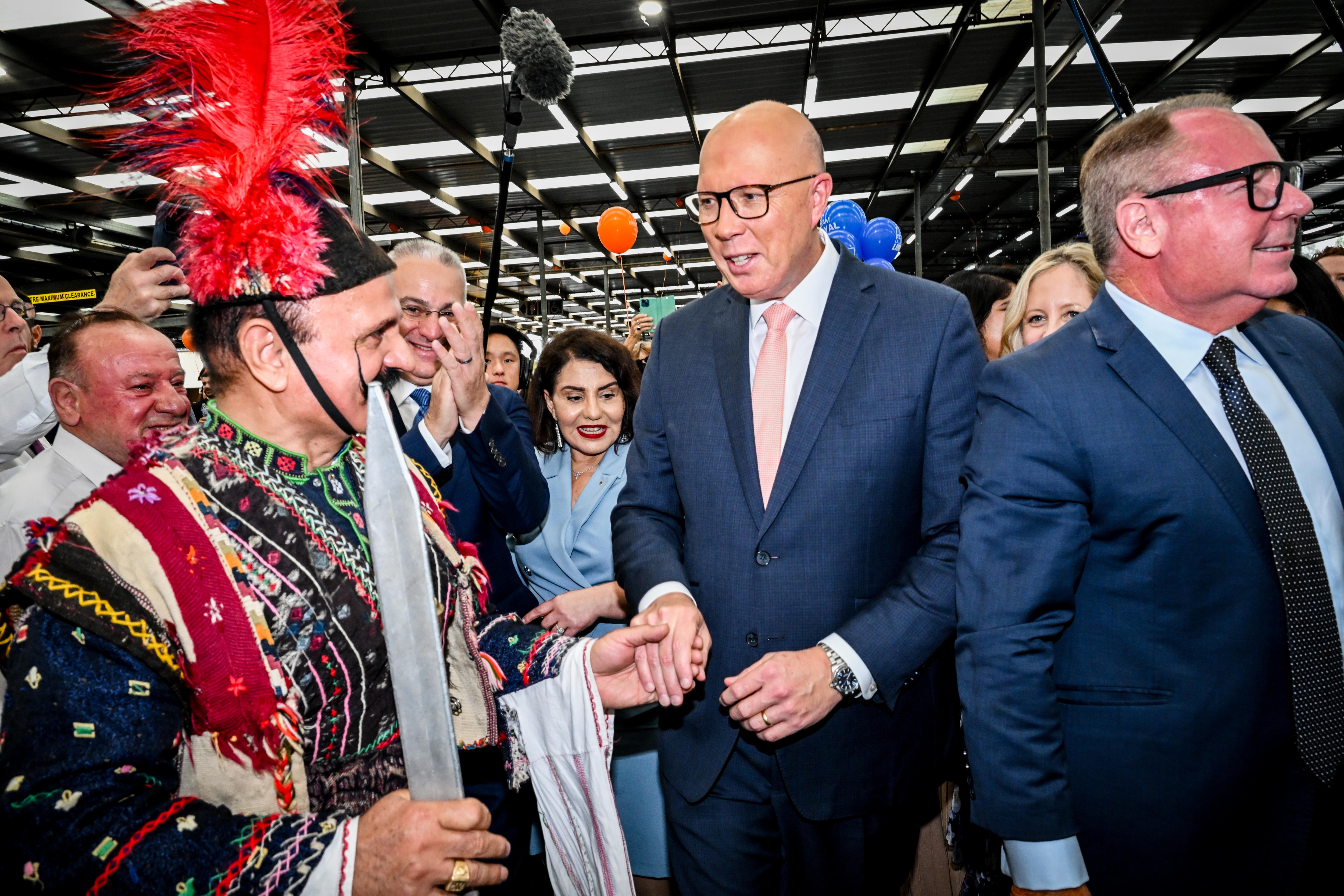 Dutton holds hands with a man in traditional costume who is dancing. 