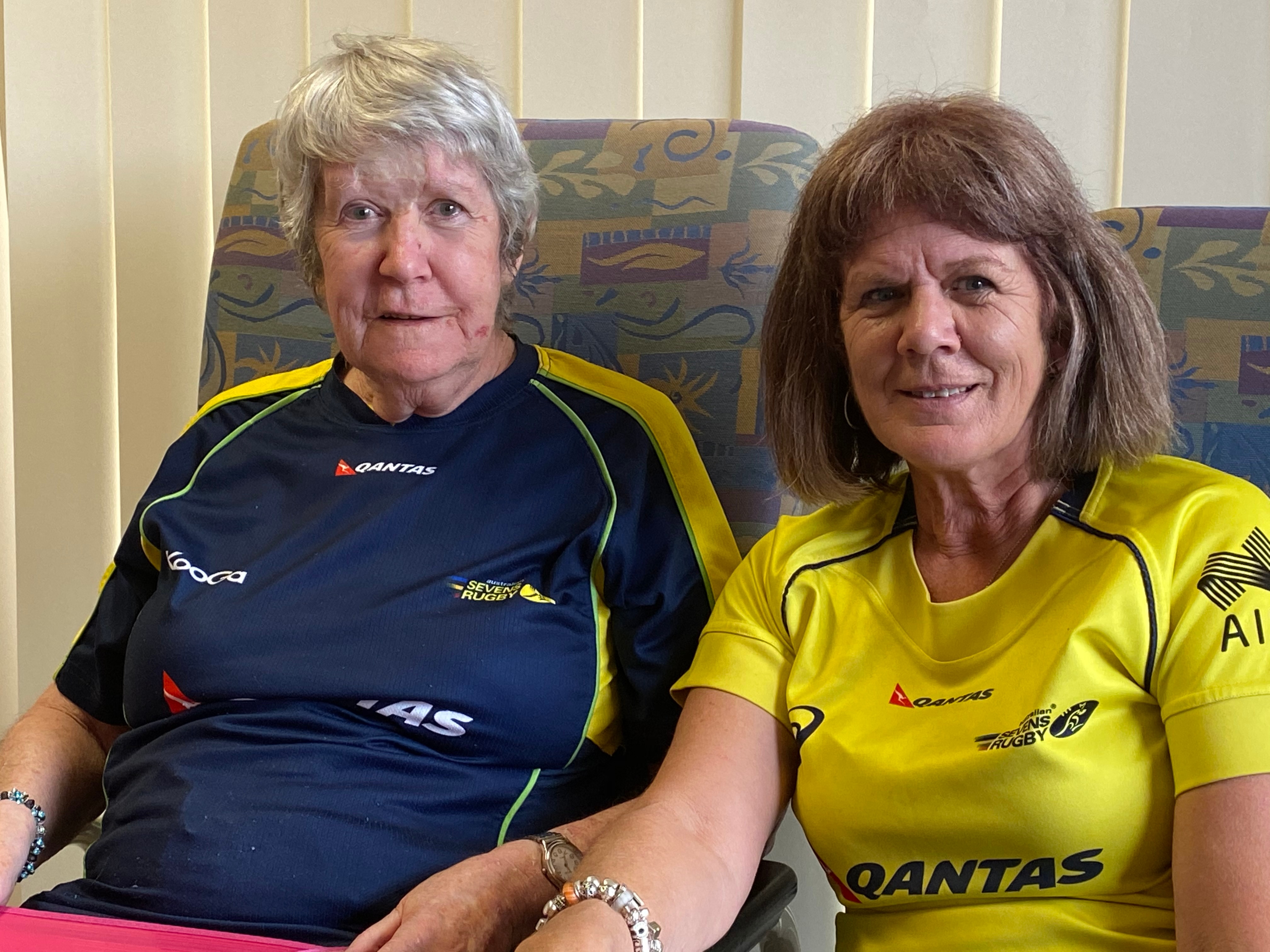 A lady in a blue shirt sitting beside a younger women in a gold shirt