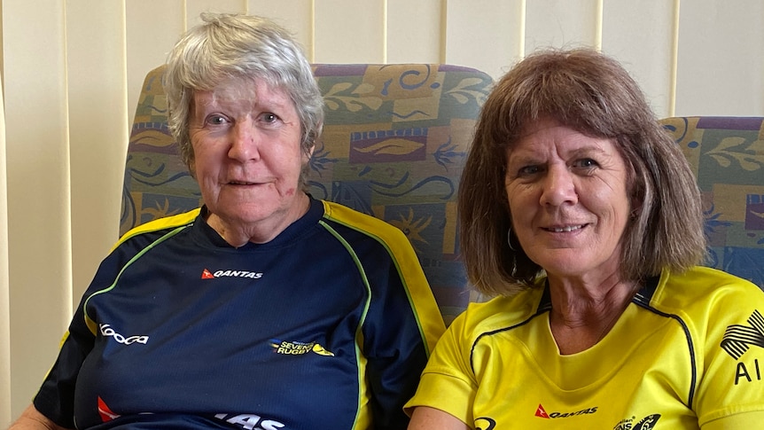 A lady in a blue shirt sitting beside a younger women in a gold shirt