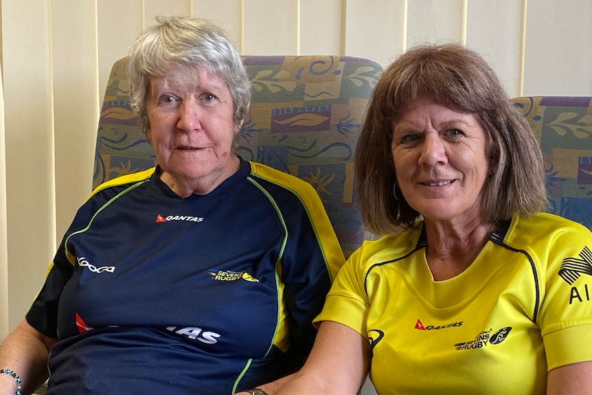 A lady in a blue shirt sitting beside a younger women in a gold shirt