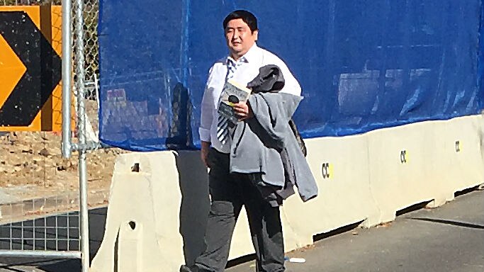 Chang Kee Song walks by construction near the court.