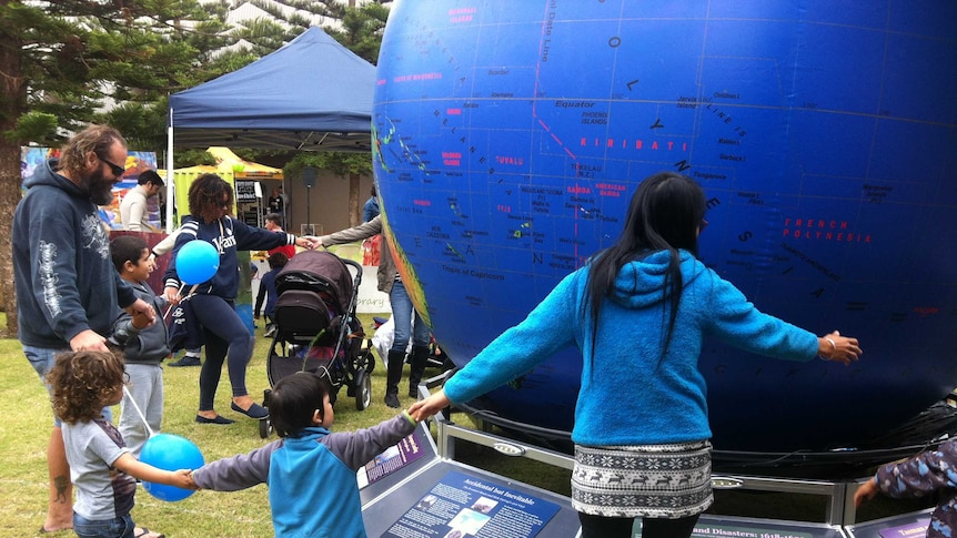Adults and children gather around inflatable 'Discoverers' Globe'