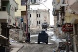 Military vehicles move through the deserted streets of Silvan.
